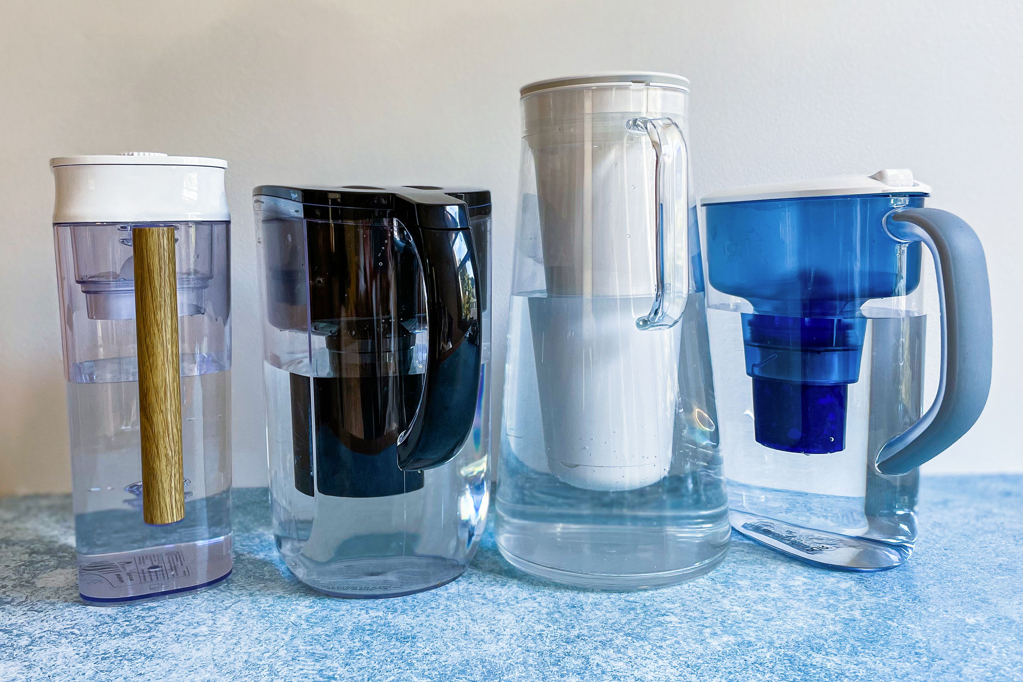four full water pitchers sitting on a blue surface