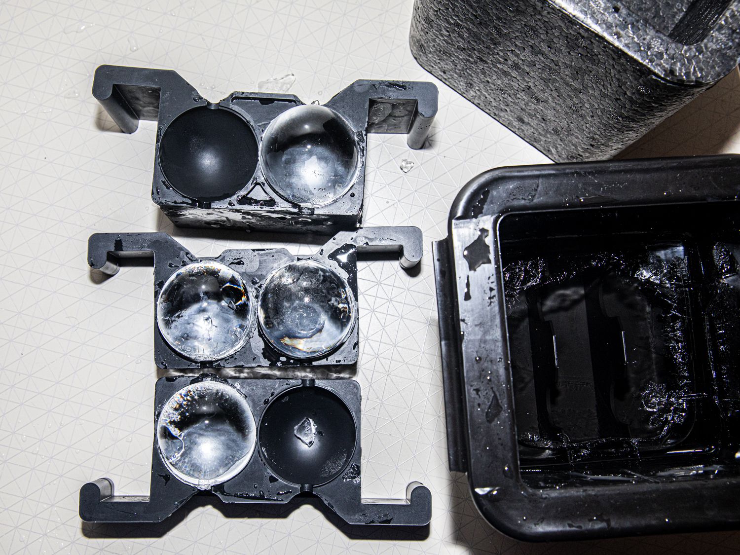 Four sphere ice cubs in their tray with their insulation beside them