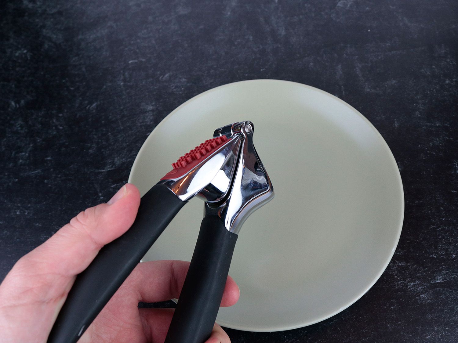 a hand holds a garlic press, showcasing the comfortable handles
