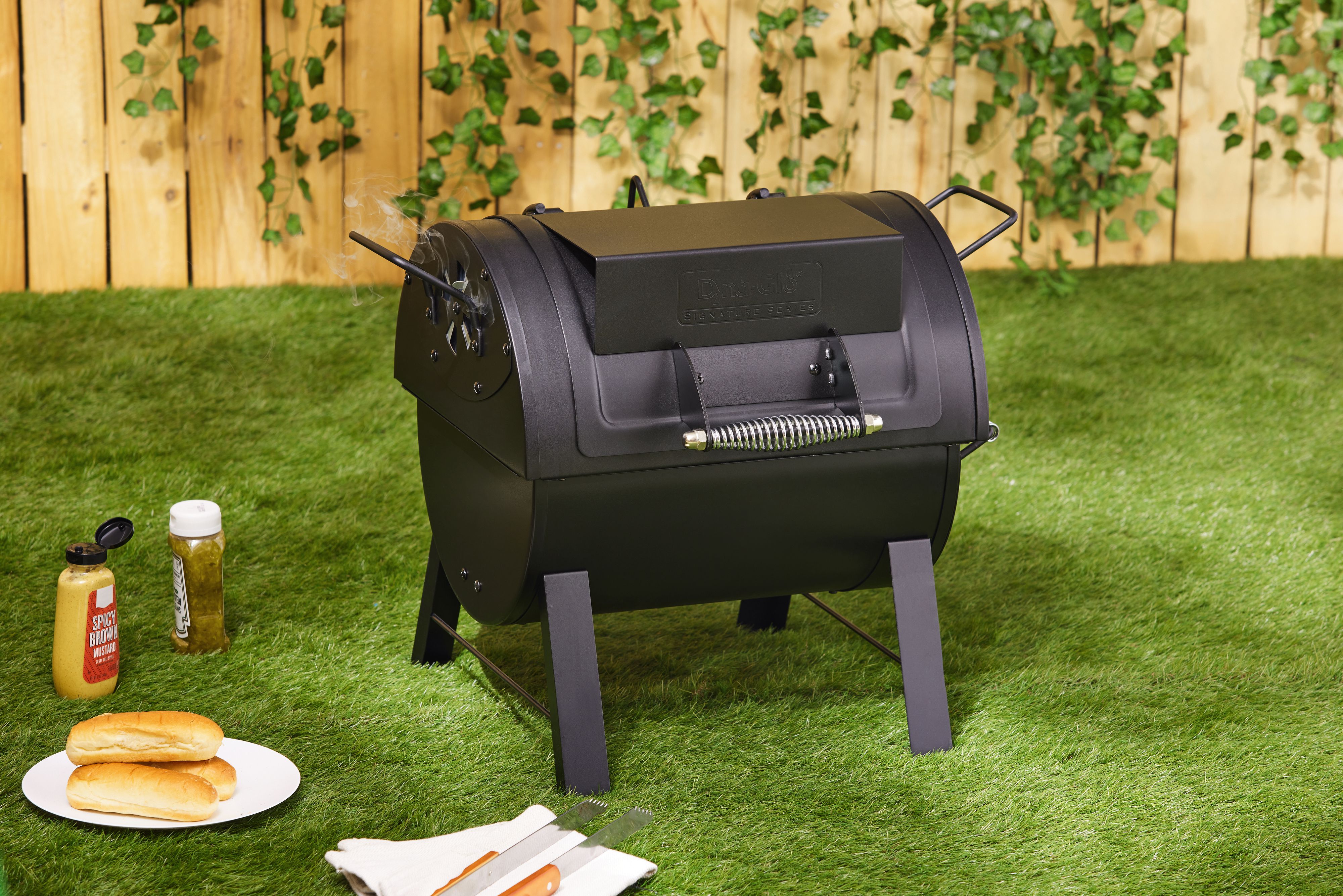 A portable charcoal grill on a lawn with its lid closed
