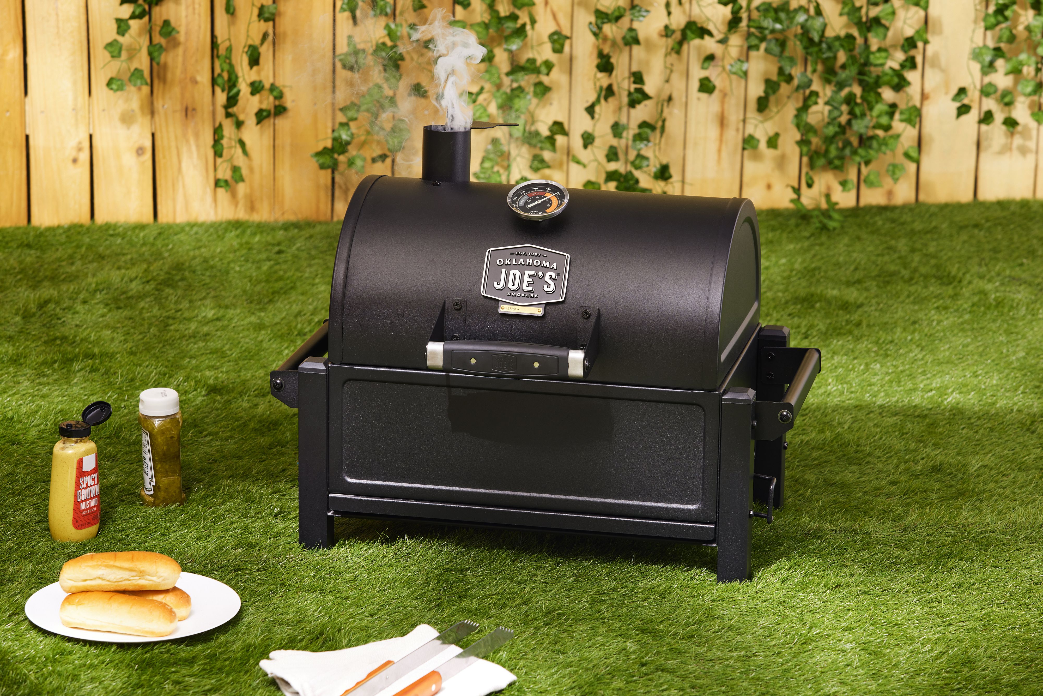 a portable charcoal grill with its lid closed and smoke venting out of its chimney