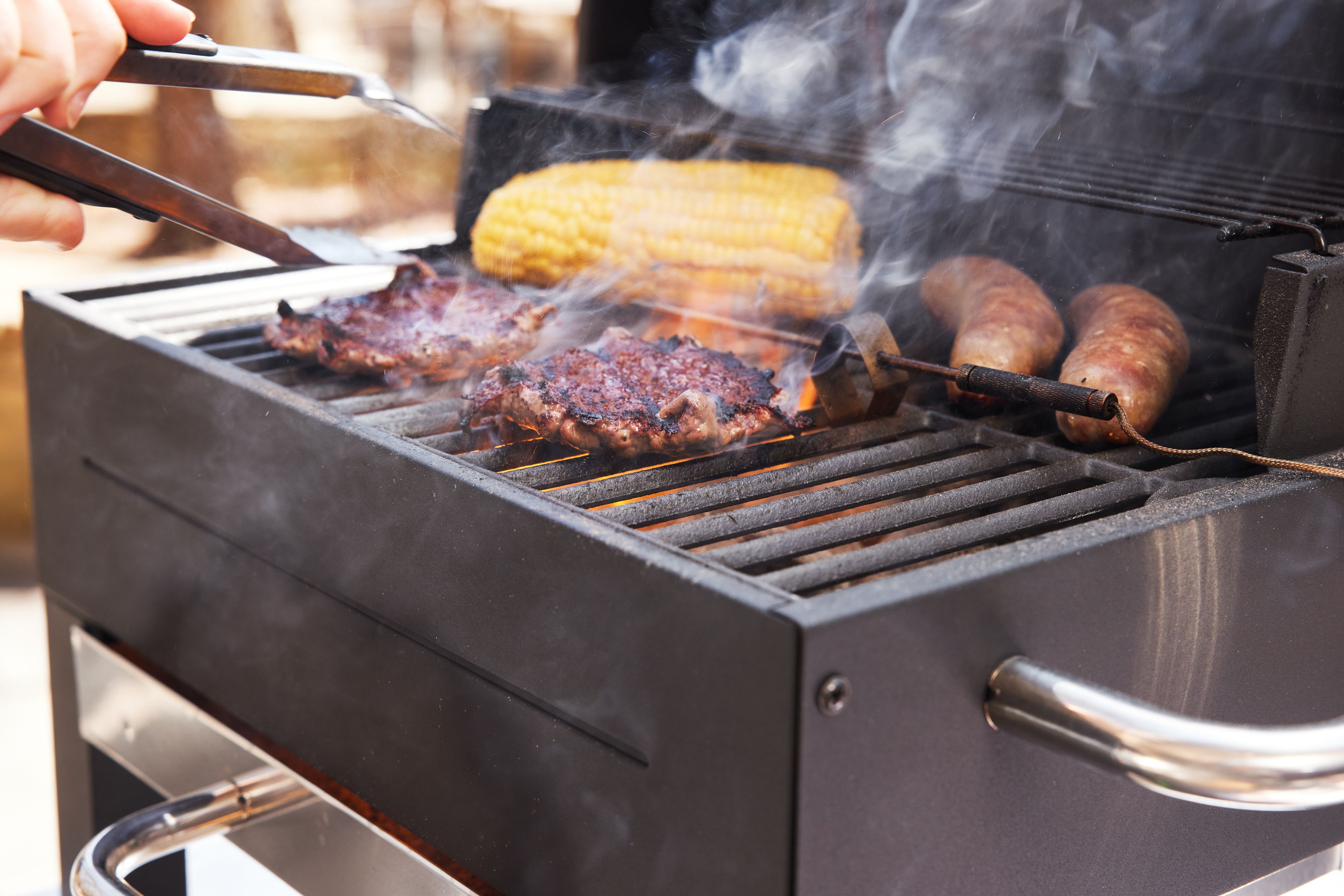 A closeup look at burgers cooking on a portable charcoal grill